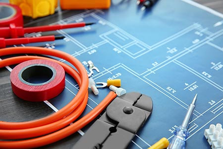 Electricians tools and cables on top of electrical rewiring blueprint