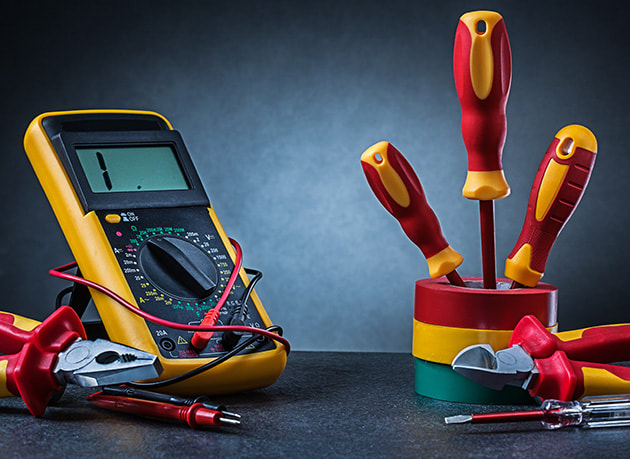 Electrical tools such as voltmeter screw drivers and wires set up on a table for a photo